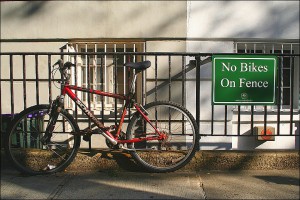 Fahrrad, das trotz eines Verbotsschildes an einen Zaun angeschlossen ist